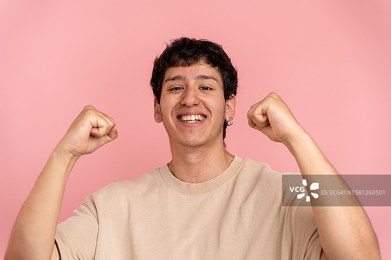 在粉色背景下庆祝好消息的年轻男子肖像图片素材