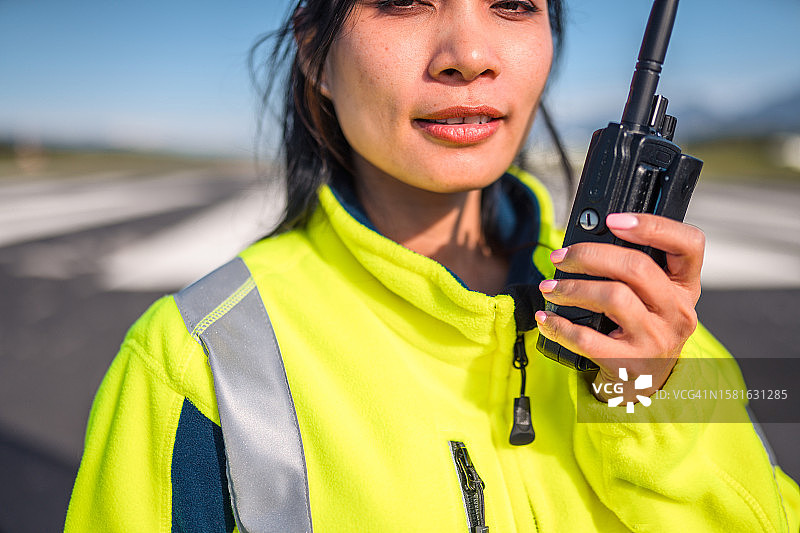 亚洲女性机场地面指挥员用对讲机汇报情况图片素材
