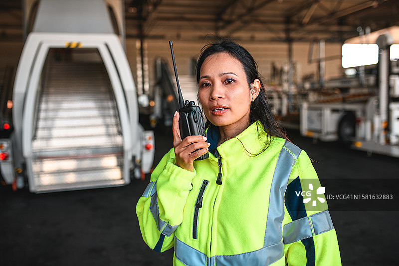 手持对讲机的亚洲女机场工作人员图片素材