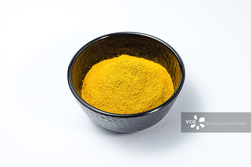 白色背景黑色碗中的姜黄粉图片素材