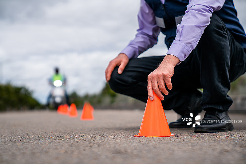 摩托车驾驶教练在地面上放置交通锥图片素材