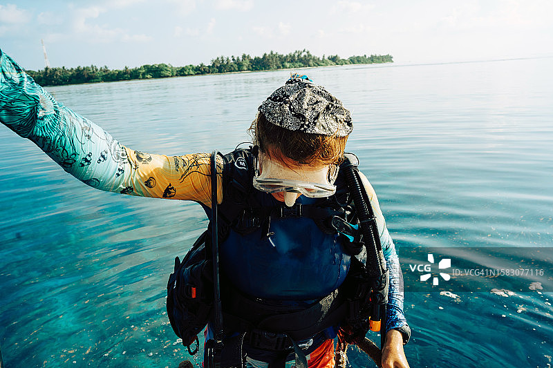 穿着潜水服的红发女人从水中爬梯子上船图片素材