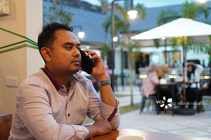 年轻的亚洲男子在咖啡店里打电话图片素材
