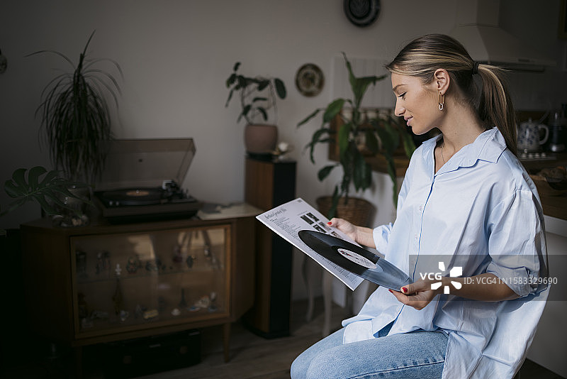 在家中手持黑胶唱片的年轻女子图片素材