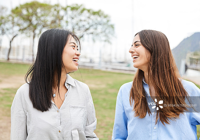 两个快乐的跨种族朋友在城市户外一起散步，笑容满面图片素材