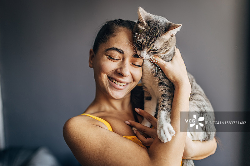 年轻漂亮的女子和她的猫在家图片素材