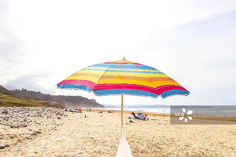 多云夏日海滩上的彩色雨伞图片素材