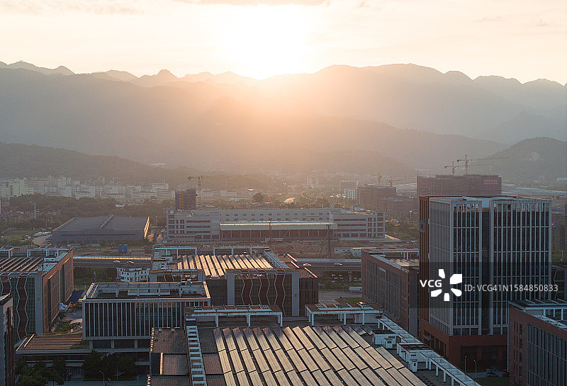 日落时分生态友好建筑上的屋顶太阳能发电厂图片素材