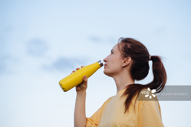 运动中欢快女孩拿着水瓶喝水图片素材