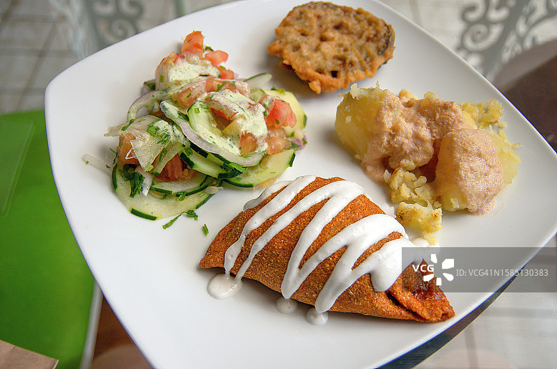 印度风味纯素开胃菜拼盘：黄瓜番茄沙拉、花椰菜土豆、炸茄子和蔬菜萨摩萨图片素材