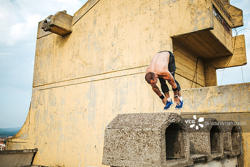 在建筑物屋顶上跑酷的健壮男人图片素材