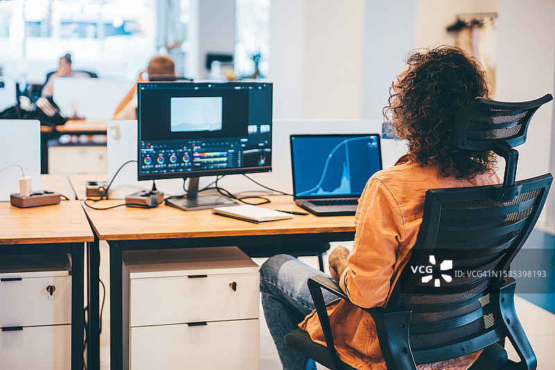 自由职业者在联合办公场所工作。男人在电脑上进行视频编辑图片素材