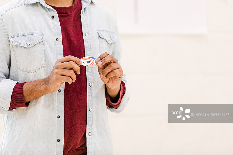 无法辨认的首次投票者自豪地展示“我已投票”贴纸图片素材
