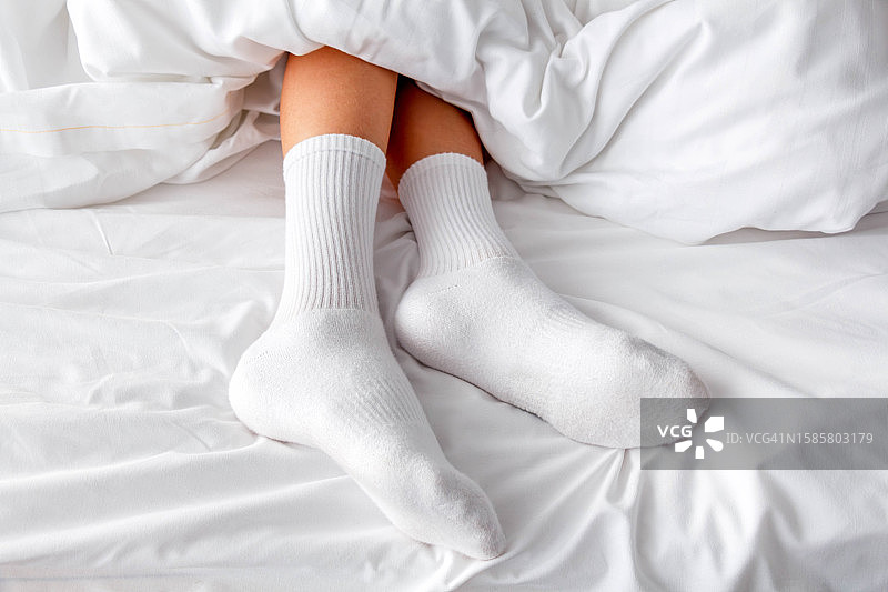躺在床上的穿着白色袜子的男孩的脚图片素材