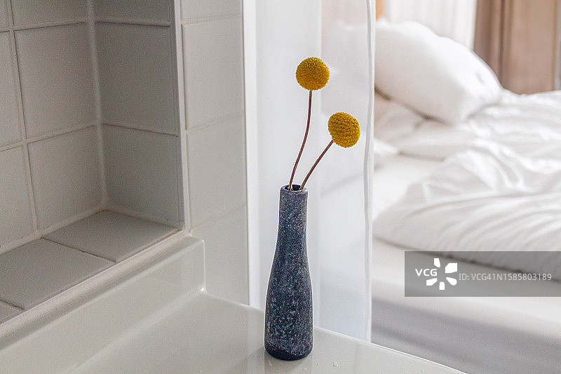 花瓶中金槌花，背景是未整理的床铺图片素材