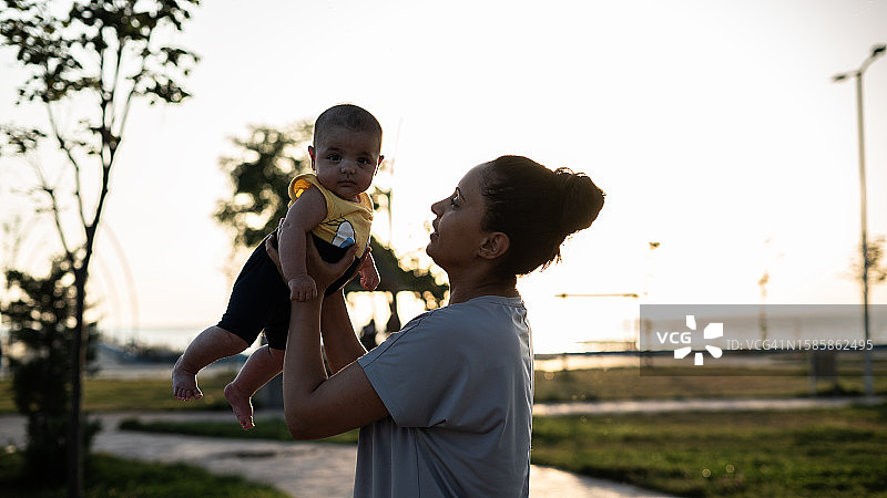 日落时分母亲将婴儿举向天空图片素材