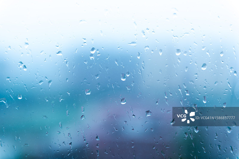 阴雨多云天气玻璃上的水滴：从窗户看到的城市景观图片素材