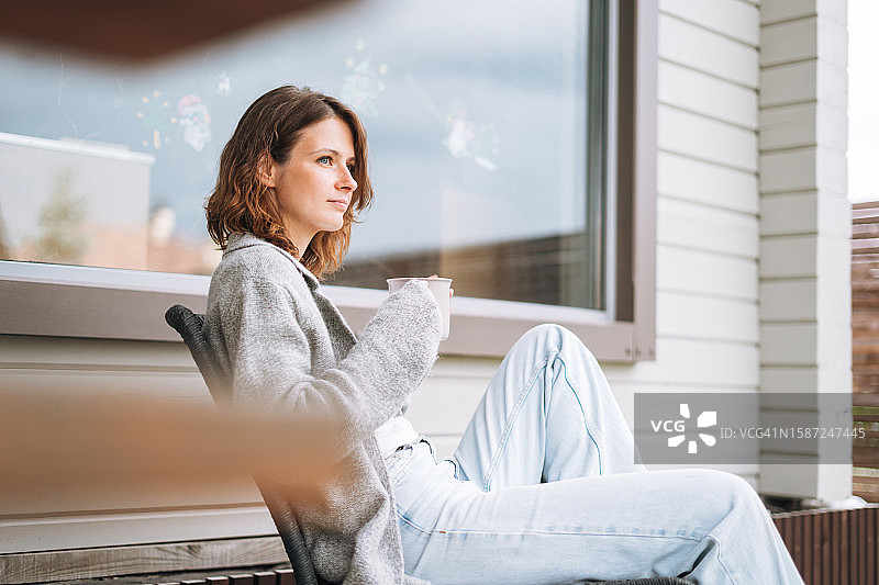 年轻女子在后院椅子上喝早咖啡图片素材