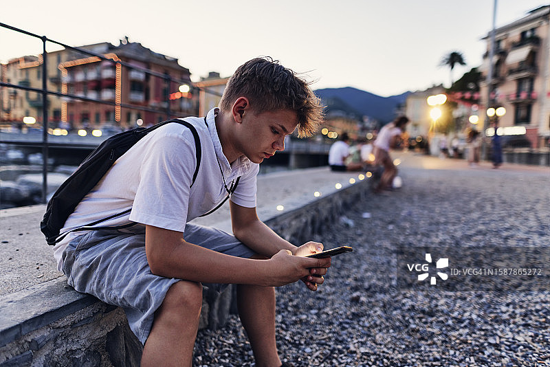 青少年男孩坐在拉帕洛长廊上使用智能手机图片素材