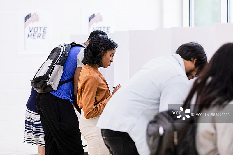 年轻女性认真阅读选票，参与总统选举图片素材