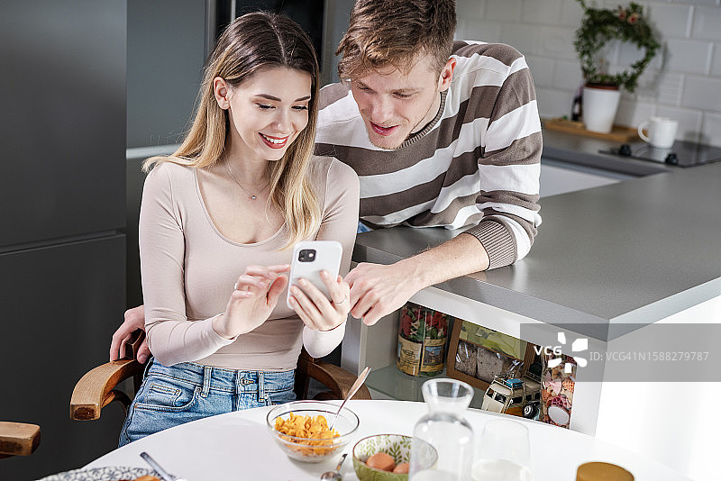 年轻情侣在早餐时看手机图片素材