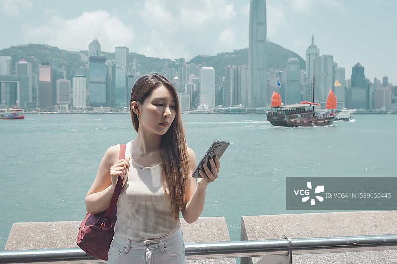 在中央商务区阅读智能手机邮件的亚洲女商人。商务旅行概念图片素材