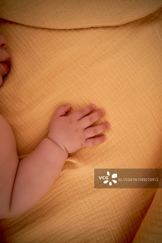 宝宝的手放在黄色棉布襁褓上图片素材