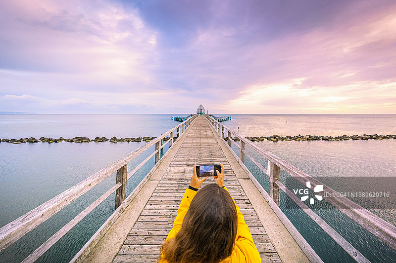女子在德国塞尔林日出时用智能手机拍照图片素材