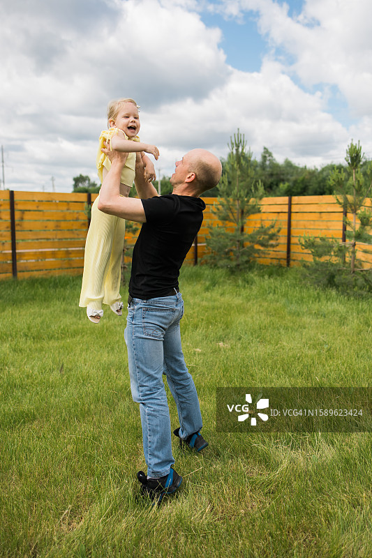 父亲在花园里和戴着人工耳蜗的听障女儿玩耍图片素材