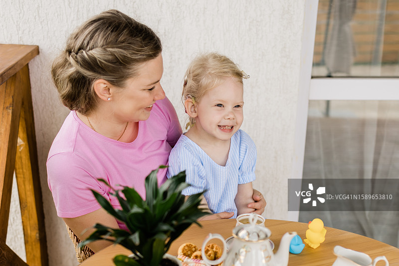 母亲与戴人工耳蜗的孩子在露台。听力受损术后适应图片素材