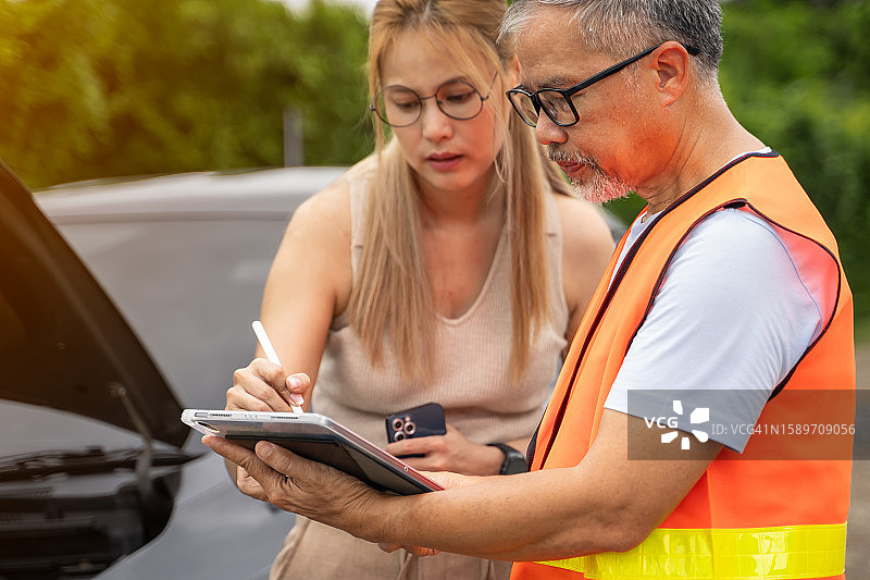 年轻女人站在受损的汽车旁，向保险公司代表报告交通事故图片素材