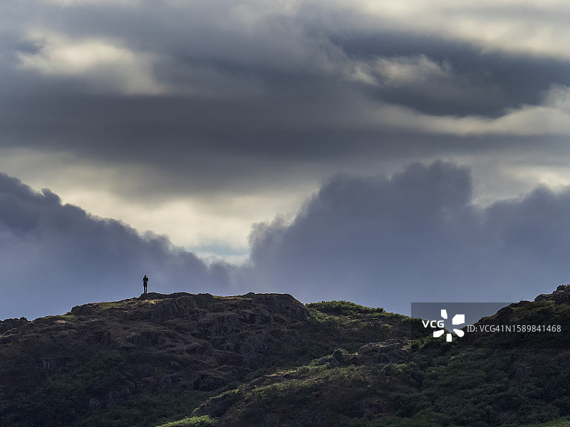 一名男子在英国湖区安布尔赛德上方的托德山峰上，乌云密布图片素材