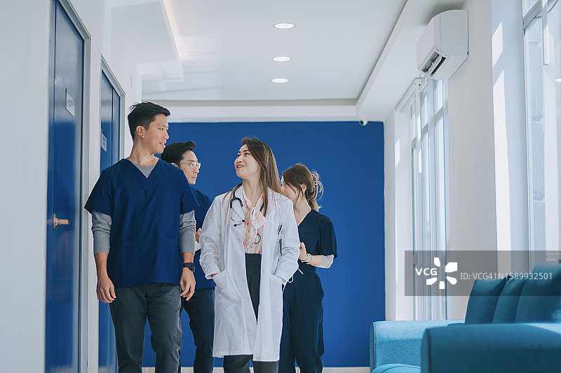 在医院接待台附近，中国医生和护士在走动时一起讨论病人诊断治疗工作图片素材