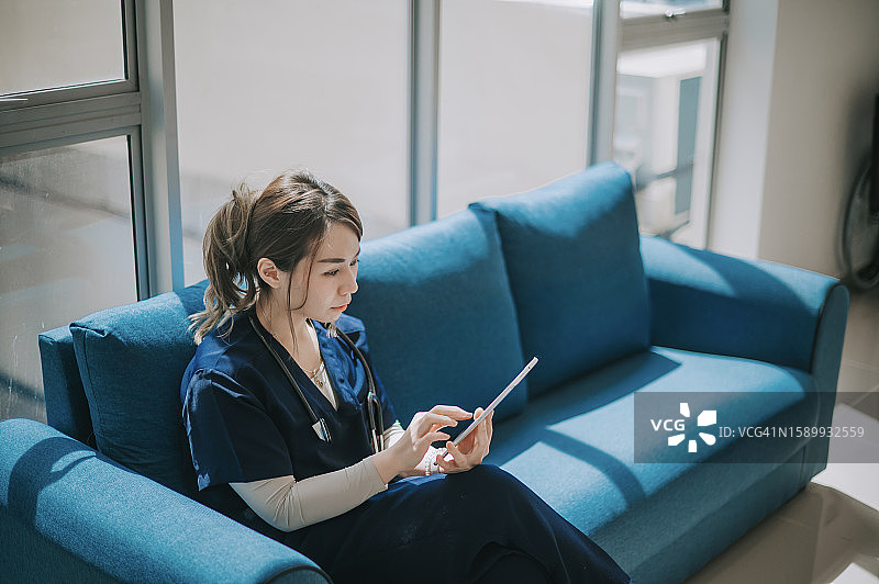 中国女医生在沙发上阅读平板电脑图片素材