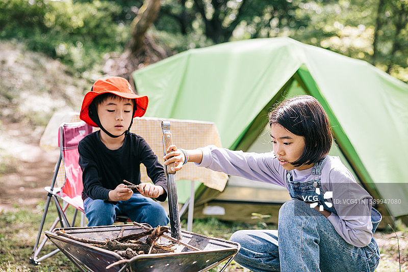 日本兄妹一起为露营篝火收集树枝图片素材