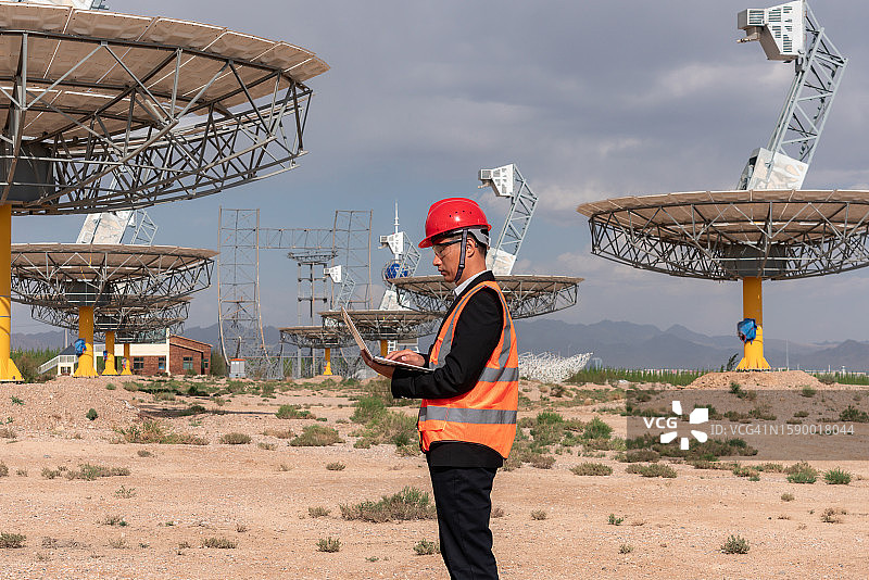 电力工人在太阳能热发电厂使用笔记本电脑图片素材