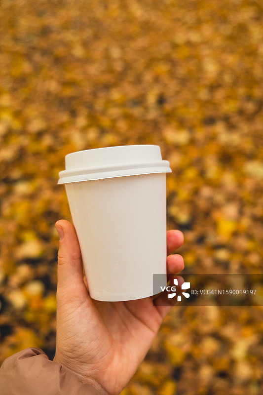 手持一次性杯子，背景为树木图片素材