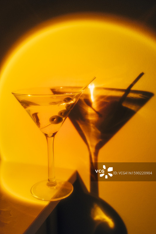 橙色霓虹灯背景上的马提尼鸡尾酒杯图片素材