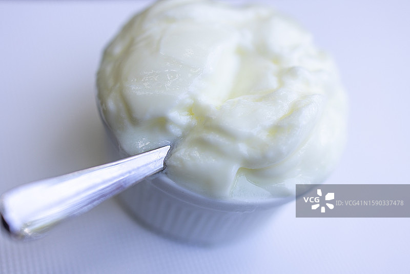 白色背景下银勺中的原味酸奶图片素材