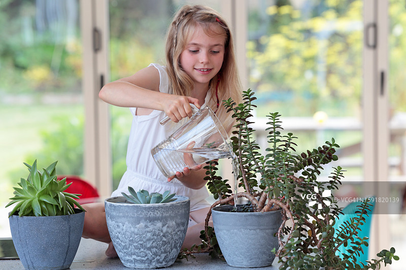女孩用大水壶浇灌植物图片素材