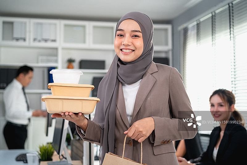 穆斯林上班族展示快递员送到办公室的一盒食物图片素材