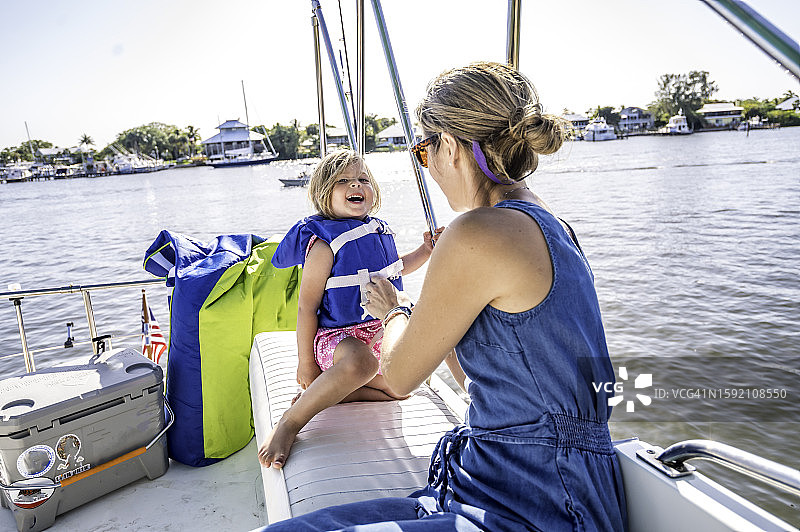 女人在帆船上为一个小孩穿好救生衣图片素材