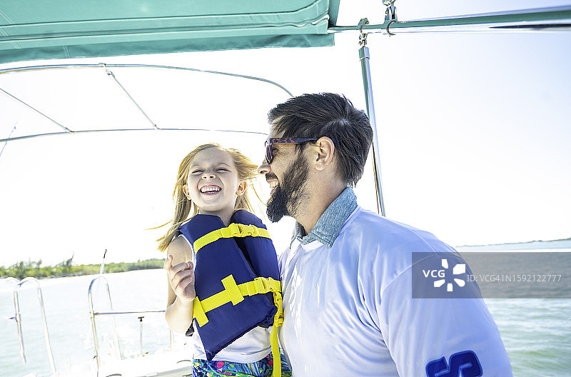 父女在阳光明媚的游船上欢笑图片素材