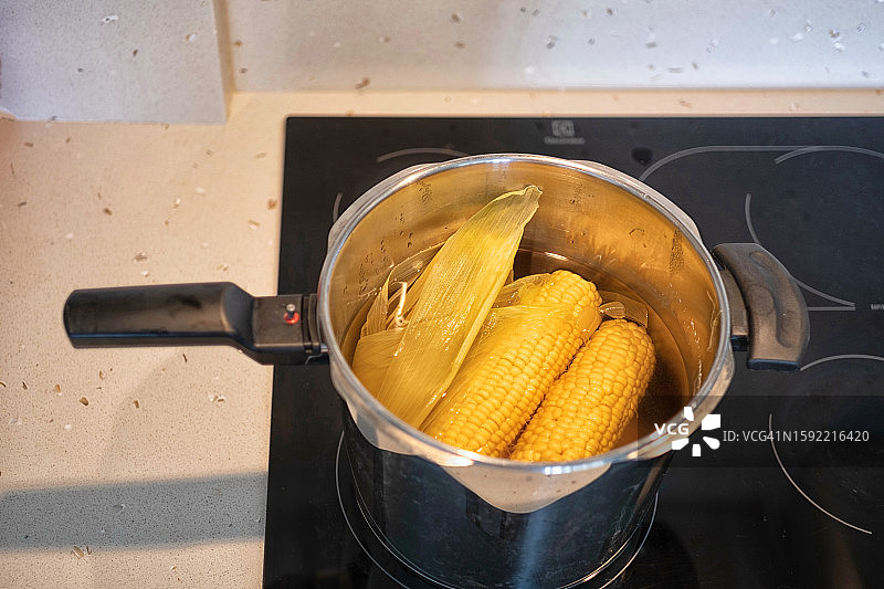 陶瓷炉灶上压力锅中煮熟的玉米（高角度拍摄）图片素材