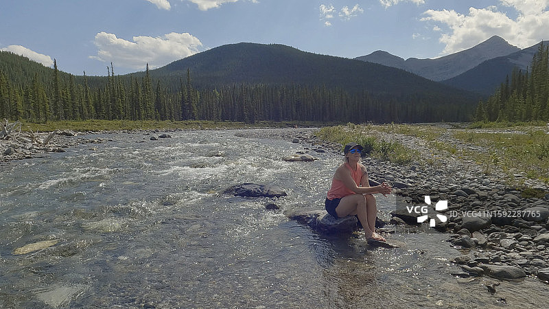 在溪流岩石上放松的女人图片素材
