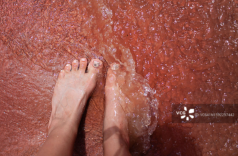 鲍威尔湖：暴雨中，女人站在红色岩层的水坑中图片素材