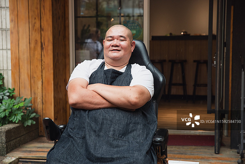 咖啡店老板坐在轮椅上，为他们的咖啡店感到自豪图片素材