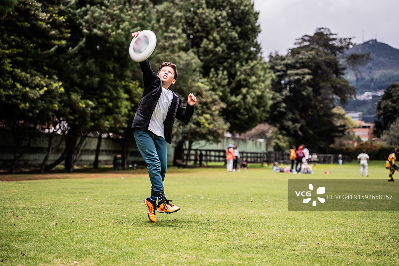 男孩在公园里跳跃着接飞盘图片素材