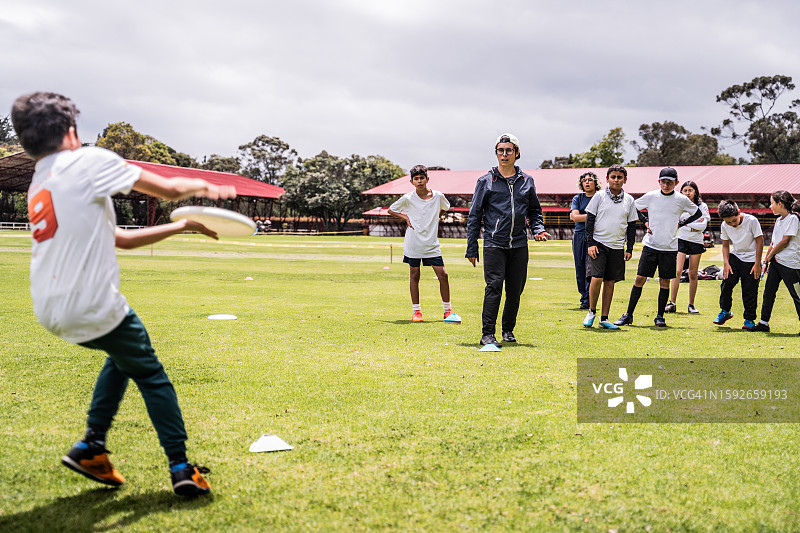 教练在运动场上向学生教授飞盘基础知识图片素材