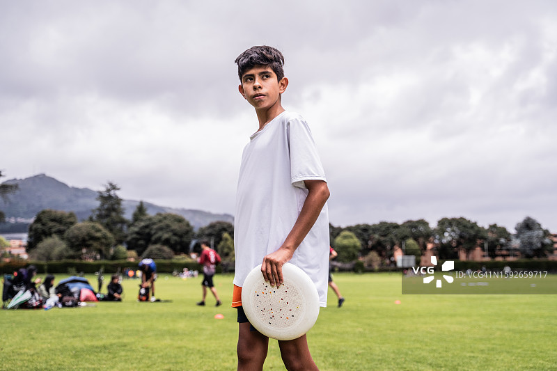 运动场上拿着飞盘望向远方的男孩图片素材